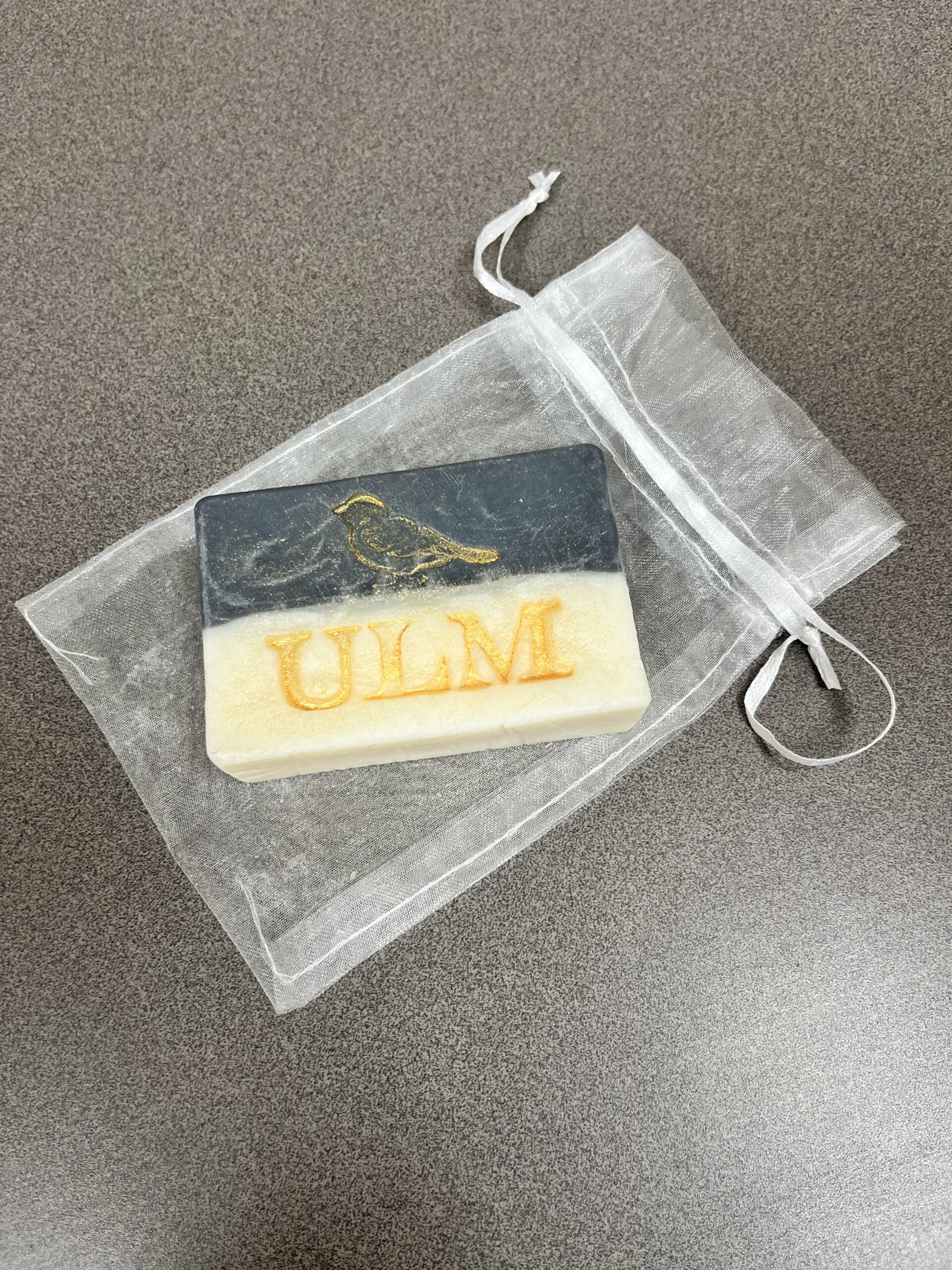 bar of soap embossed with a sparrow and the word Ulm placed in a satin bag