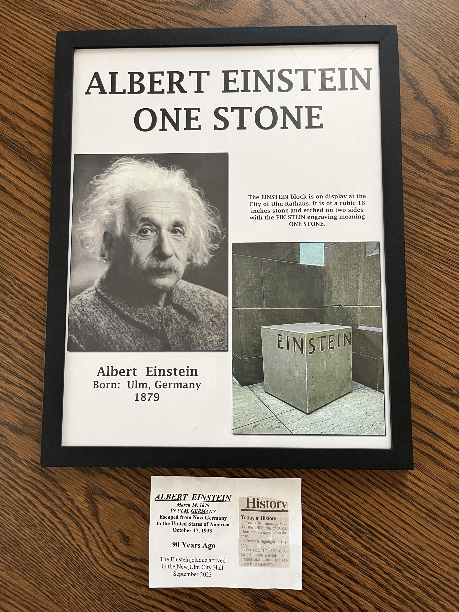 Framed photo of Albert Einstein and One Stone block on display at City of Ulm Rathaus. Cubic 16 inch stone is etched on two sides with the EIN STEIN engraving meaning one stone.